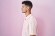 © Krakenimages.com - Young hispanic man standing over pink background looking to side, relax profile pose with natural face and confident smile.