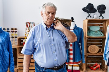 Sticker - Senior man with grey hair holding shopping bags at retail shop thinking attitude and sober expression looking self confident