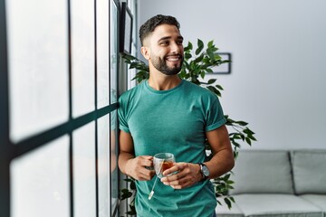 Wall Mural - Young arab man smiling confident drinking tea at home