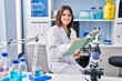 © Krakenimages.com - Young beautiful hispanic woman scientist smiling confident writing notebook at laboratory