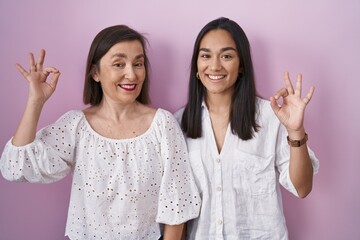 Wall Mural - Hispanic mother and daughter together smiling positive doing ok sign with hand and fingers. successful expression.