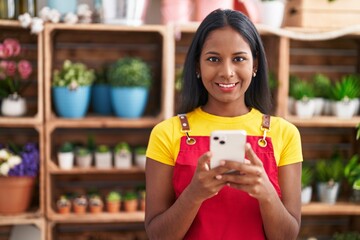 Canvas Print - Young beautiful woman florist smiling confident using smartphone at florist