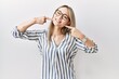 © Krakenimages.com - Asian young woman wearing casual clothes and glasses smiling cheerful showing and pointing with fingers teeth and mouth. dental health concept.