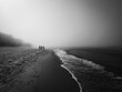 spacerujące osoby nad brzegiem morza w letni mglisty poranek 