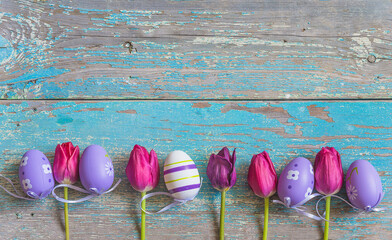 Wall Mural - Easter holiday background; Frame of easter eggs and purple tulips on old blue paint wooden background; flat lay, copy space