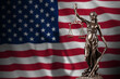 United States of America flag with statue of lady justice and judicial scales in dark room. Concept of judgement and punishment