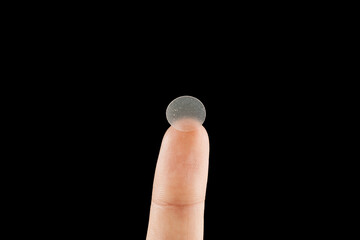 close-up round acne patch on finger on black background. acne patches for treatment of pimple and ro
