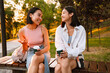 © Drobot Dean - Two asian women talking and drinking coffee while sitting on bench