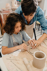 Wall Mural - Mature woman teaching boy to make clay crafts at workshop