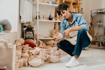 Wall Mural - Mature woman looking at pottery handcrafts at the workshop