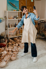 Wall Mural - Mature woman making videocall and gesturing while standing at workshop