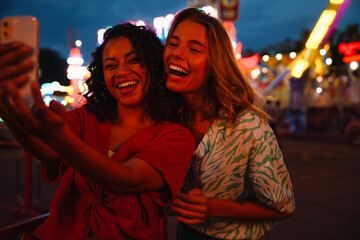 Wall Mural - Two young beautiful happy enthusiastic girls taking selfie on phone