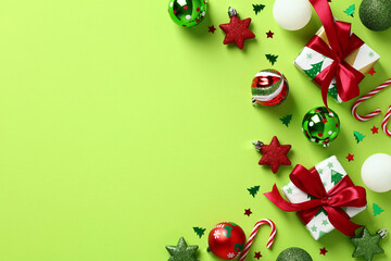 Wall Mural - Green Christmas background with festive gift boxes, baubles, stars, confetti on light green table. Top view. Flat lay.