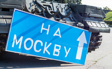 Blue Road Sign With White Letters Near The Tank, On The Territory Of The National Museum Of The History Of Ukraine. Russia's War Against Ukraine. Translation, To Moscow.