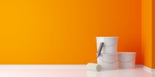 Orange Paint Roller Leaning Against White Paint Buckets In Empty Room With Orange Wall Background, Home Improvement, Renovation Or Construction Work Concept