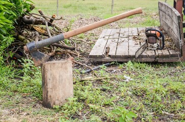 Sticker - Axe stuck in a log captured during wood cutting and a chainsaw next to it