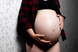 close-up belly of a pregnant girl in a plaid shirt