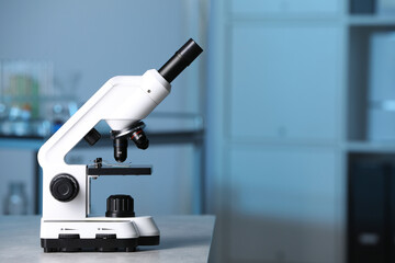 Modern medical microscope on gray table in laboratory, space for text