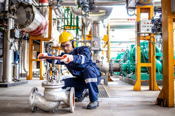 Wall Mural - Hardworking industrial technician inspecting high pressure valve inside refinery plant.