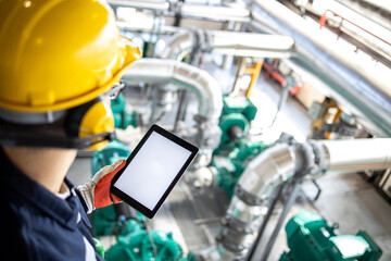 Wall Mural - Petrochemical engineer or technician holding digital tablet and controlling crude oil processing inside refinery.