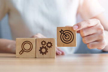 Woman hand holding dartboard, Gear and Lightbulb icon block on table. business planning process, goal, strategy, target, mission, action, objective, teamwork and research concept