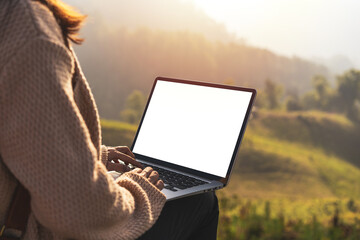 Wall Mural - Young woman freelancer traveler working online using laptop and enjoying the beautiful nature landscape with mountain view at sunrise