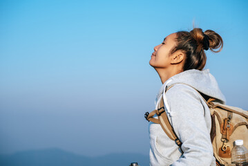 Portrait of Asian young tourist woman is hiking on the top of the mounting and looking at a beautiful landscape with copy space