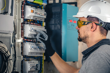 Wall Mural - Man, an electrical technician working in a switchboard with fuses.