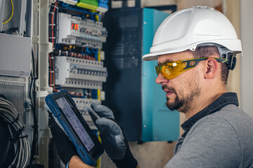 Wall Mural - Man, an electrical technician working in a switchboard with fuses.