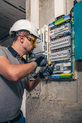 Man, an electrical technician working in a switchboard with fuses.