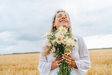 Smiling Woman Standing With Bunch Of White Flowers In Front Of Sky