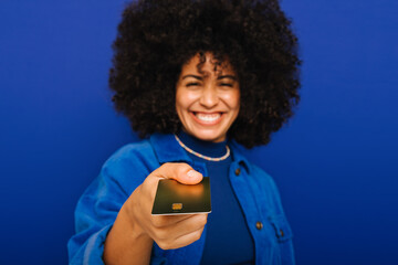 Wall Mural - Happy woman holding out her credit card in a studio