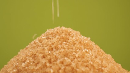 Poster - Brown sugar. Pouring brown sugar close up, green background. Demerara golden brown sugar