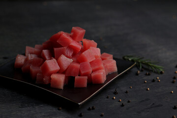 Raw fresh Tuna cube on black plate. Black wooden background.