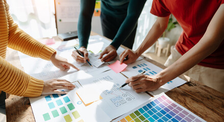  UX developer and ui designer brainstorming about mobile app interface wireframe design with customer breif and color code at office..