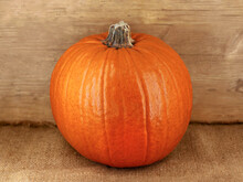 Whole Round Pumpkin On Jute Sack With Rustic Wooden Background, The Perfect Pumpkin To Carve For Spooky Halloween Faces