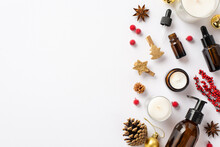 Winter Skin Care Concept. Top View Photo Of Cosmetic Bottles Candles Christmas Decor Golden Baubles Decorative Clips Pine Cone Mistletoe Berries And Anise On Isolated White Background With Empty Space