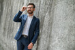 © zinkevych - An elegant young man in eyeglasses standing near the wall
