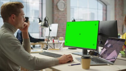 Wall Mural - Portrait of White Creative Young Man Working on Green Screen Computer During the Day in Modern Busy Office. Project Manager Smiling While Using Desktop Computer. Zoom In Shot.