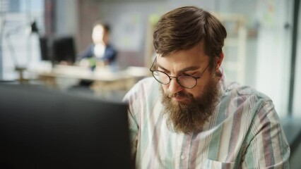 Leinwandbilder - Portrait of Young Caucasian Bearded Man with Glasses Focused and Working on Computer in a Bright Spacious Office. Male Administrator Smiling after Successfully Finishing a Task. Slow Motion Close Up