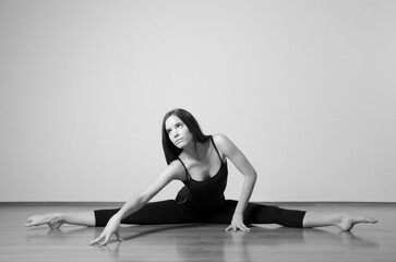 Wall Mural - Beautiful young ballerina stretching on the floor before dancing workout in ballet studio