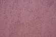Closeup of plastered exterior wall painted in mauve purple color. Indented texture background.