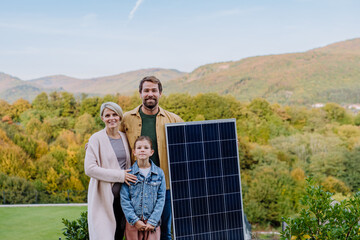 Happy family near their house with solar panel. Alternative energy, saving resources and sustainable lifestyle concept.