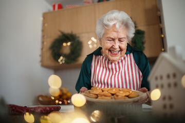 Wall Mural - Happy senior woman baking Christmas cakes at home.