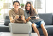 © Nassorn - Young couple having fun have fun playing video game on sofa in living room. Cheerful friends sitting together on couch happy play game. Husband and wife exciting leisure activity as relaxation at home
