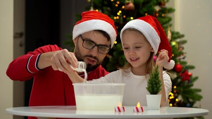 Wall Mural - Happy family, father and daughter fun make artificial snow at table at home on background of shining Christmas tree. Christmas decorations