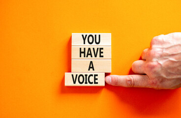 You have a voice symbol. Concept words You have a voice on wooden blocks. Beautiful orange table orange background. Businessman hand. Business, psychological you have a voice concept. Copy space.