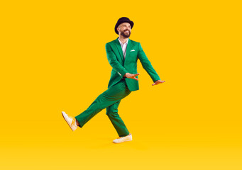 Wall Mural - specifics of irish culture. cheerful man in green modern suit and hat is dancing and having fun cele
