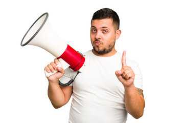 Canvas Print - Young caucasian man holding a megaphone isolated showing number one with finger.