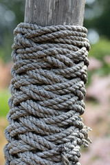 Vertical closeup of ropes tied around a wooden pole